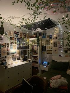 a bedroom with lots of plants hanging from the ceiling and lights on the walls above it