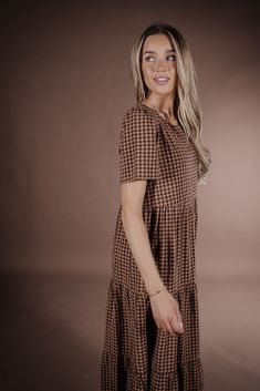 Indulge in the sophistication of the Taryn Gingham Dress on Brown. Made from 100% cotton, this midi dress boasts a modest silhouette and timeless gingham print, making it the perfect fall dress. Elevate your wardrobe with this premium piece that exudes elegance and style. 100 Cotton Model Measurements: Hips 36” Waist 25” Bust: 31”, Height 5’5.5, wearing a size small Fall Cotton Midi Dress In Brown, Brown Cotton Midi Dress For Fall, Gingham Plaid Knee-length Dress With Ruffles, Knee-length Cotton Midi Dress For Picnic, Cotton Knee-length Midi Dress For Picnic, Cotton Midi Dress For Picnics, Knee-length, Spring Midi Dress With Houndstooth Pattern, Spring Houndstooth Midi Dress, Knee-length Cotton Plaid Dress For Daywear