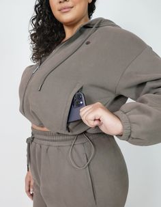 CozyCloud Jacket Feel your best in our new midweight CozyCloud Jacket, made to perfection. This bomber length jacket comes with a drawstring waistband so you can wear it full or adjust it to your desired length. Made with large kangaroo pockets. Completed with an oversized hoodie and beautiful gunmetal hardware. Made from our TeddyPlush fabric to keep you bundled up feeling like you're embraced by a cozy cloud. Perfectly paired with our CozyCloud Joggers or Effortless Leggings - Driftwood Featur Athleisure Outerwear With Kangaroo Pocket For Loungewear, Comfy Outerwear With Adjustable Hood For Loungewear, Comfy Outerwear With Drawstring Hood And Relaxed Fit, Comfy Relaxed Fit Outerwear With Pockets, Comfy Relaxed Fit Outerwear With Kangaroo Pocket, Athleisure Outerwear With Drawstring For Fall, Winter Outerwear With Drawstring And Relaxed Fit, Winter Relaxed Fit Outerwear With Drawstring, Comfortable Long Sleeve Outerwear With Kangaroo Pocket