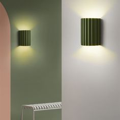 two green lamps on the wall next to a white bench