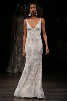 a model walks down the runway in a beaded gown