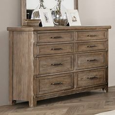 a wooden dresser sitting next to a mirror on top of a hard wood flooring