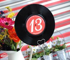 there is a record with the number thirteen on it and flowers in vases behind it