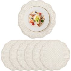 a white plate topped with fruit on top of a pile of placemats next to each other