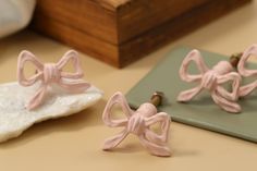 two pink bow shaped earrings sitting on top of a table