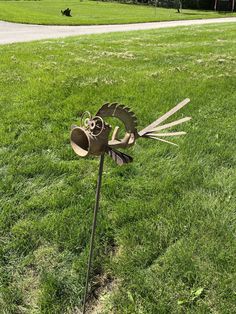 a metal wind sculpture sitting on top of a lush green field