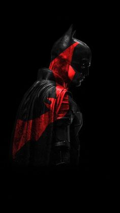 a man dressed in black and red with a batman mask on his face, standing against a dark background