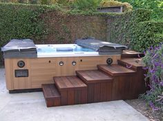 an outdoor hot tub with steps leading up to it and purple flowers in the background