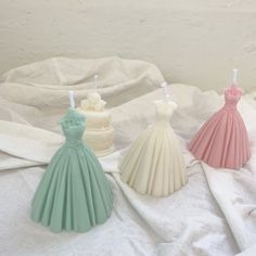 three different colored dresses sitting on top of a white sheet next to eachother