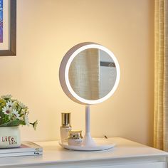 a white table with a mirror on top of it and a flower pot next to it