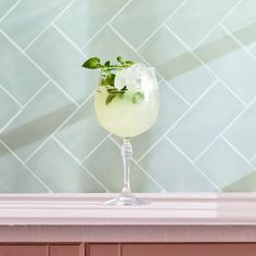 a glass filled with lemonade sitting on top of a counter next to a tiled wall