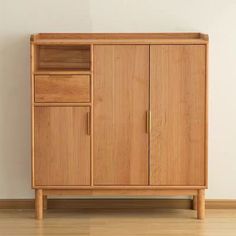 a wooden cabinet sitting on top of a hard wood floor next to a white wall