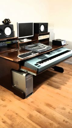 a computer desk with two monitors, keyboard and speakers sitting on top of each other