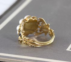 "An immaculate antique Georgian mourning ring, crafted in 18k yellow gold with a lustrous split pearl halo around the center compartment which holds a momento of woven hair under crystal. The shoulders are delicately articulated in a baroque scroll design, accented by glossy black enamel, and the ring is fully hallmarked for 18k, London manufacture, and letter dated 1828. Measuring approximately 1/2\" north to south at the center front, tapering through the shoulders to 2.22 mm at the center bac Victorian Enamel Ring For Anniversary, Victorian 14k Yellow Gold Pearl Ring, Victorian Style 14k Yellow Gold Pearl Ring, Antique Yellow Gold 14k Pearl Ring, Antique Hallmarked Enamel Wedding Ring, Victorian Enamel Wedding Ring, Antique Gold Pearl Ring In 14k Gold, Victorian Yellow Gold Enamel Ring, Victorian Gold Enamel Ring