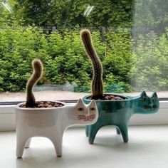 two cat planters sitting on top of a window sill next to each other