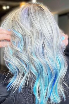 Icy blue streaks in platinum blonde hair create a cool, modern look. These streaks give a frosty edge to your hairstyle. Click here to check out more best peek a boo highlights ideas to try this year. Blonde Balayage With Blue Highlights, Peek A Boo Hair Silver, Blonde Hair Blue Underlayer, Long Blonde Hair With Color Peekaboos, Turquoise And Blue Hair, Colored Streaks In Blonde Hair, Peek A Book Hair Color, Blue And Blonde Hair Peekaboo Highlights, Blue Balayage Blonde