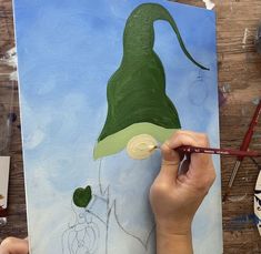 someone is painting a green hat on a piece of paper