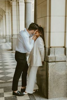 a man and woman standing next to each other in front of a building with columns