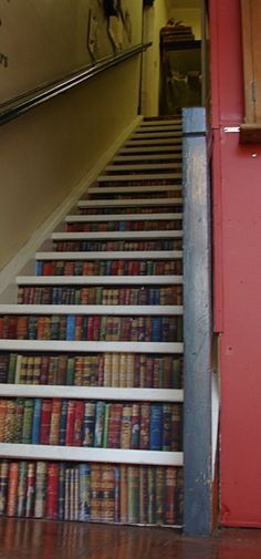 a stair case with books on it next to a red door