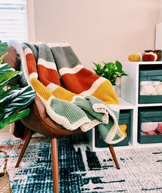 a chair with a blanket on top of it in front of a potted plant