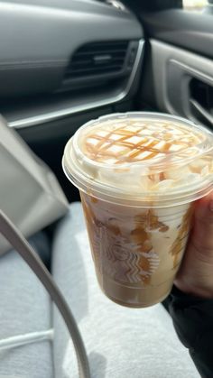 a person holding a cup of coffee in their hand while sitting in the driver's seat of a car