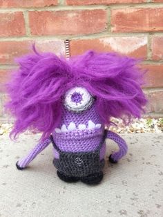 a crocheted toy with purple hair and eyes