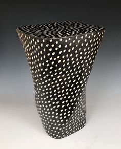 a black vase with white dots on it