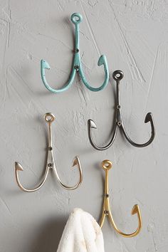 three hooks are attached to the wall with towels hanging from them and one hook is holding an umbrella