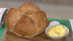 a loaf of bread sitting on top of a cutting board next to a bowl of butter