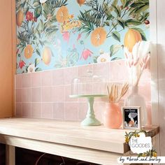 a table with a cake on top of it in front of a floral wallpaper