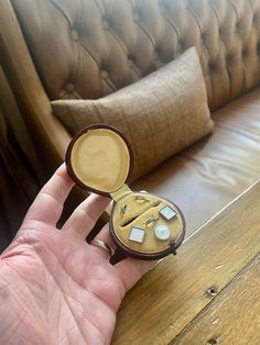 a person holding a small wooden object in their hand on a table next to a couch