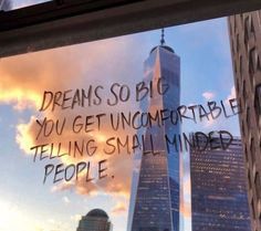 there is a message written on the window in front of skyscrapers that say, dreams so big you get uncomfortableable telling small minds people