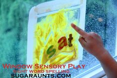 a child pointing at a window with the words window sensory play written on it