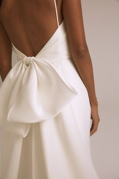 the back of a woman's wedding dress with a large bow on her shoulder