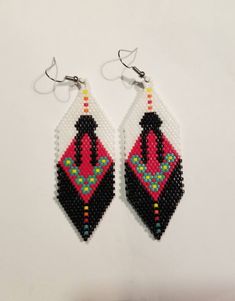 two pairs of beaded earrings with black, red and white designs on them hanging from hooks