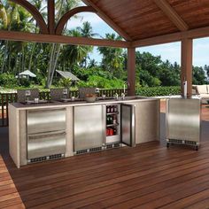 an outdoor kitchen with stainless steel appliances on a deck next to a couch and table