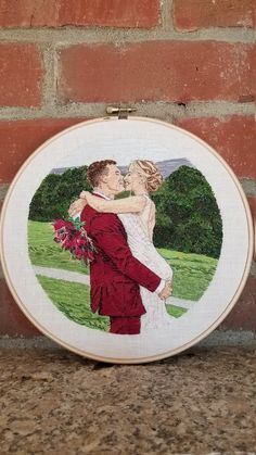 a cross stitch picture of a bride and groom kissing in front of a brick wall