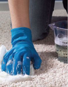 a person in blue gloves cleaning the floor