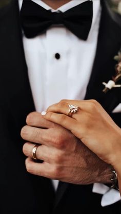 a man in a tuxedo holds the hand of a woman wearing a wedding ring