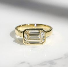 a gold ring with an emerald cut diamond