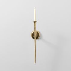 a candle that is on the wall next to a white wall with a gold handle