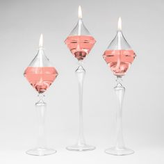 three clear candlesticks sitting next to each other in front of a white background