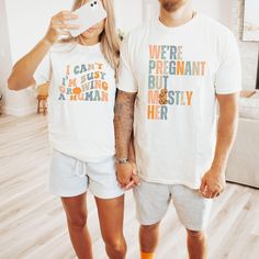 a man and woman standing next to each other wearing matching t - shirts that say i can't pregnant, but my husband is mostly her