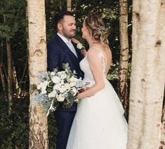 a bride and groom standing in front of some tall trees at their outdoor wedding ceremony