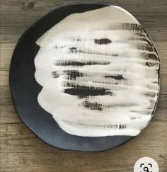 a black and white plate sitting on top of a wooden table