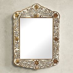 an ornate mirror with gold trimmings and flowers on the border, against a white background