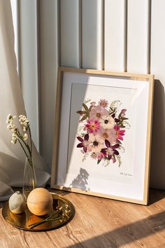 a vase with flowers sitting on a table next to a framed photograph and two eggs