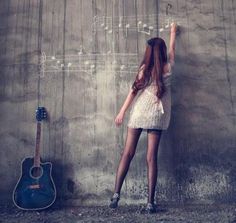 a girl standing in front of a wall with an acoustic guitar on it's side