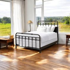 a bedroom with hardwood floors and large windows overlooking the green field in front of it