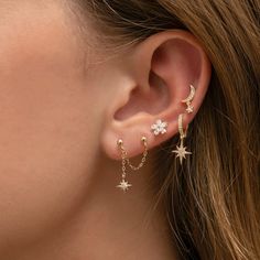 a close up of a woman's ear with stars and moon earrings on it